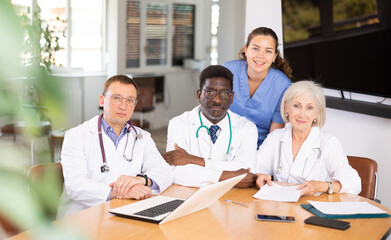 Fototapeta premium In conference room, doctors pose after successful meeting for final report. Snapshot of positive prosperous clinic staff for social networks and promotion of clinic sales