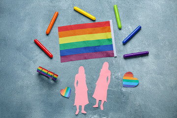 LGBT flag with paper female figures, hearts, belt and pens on grunge background