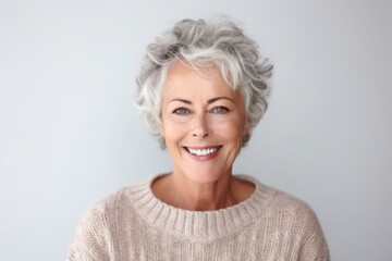 Fototapeta na wymiar Portrait of a beautiful senior woman smiling at the camera on gray background