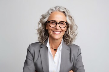 smiling senior businesswoman in eyeglasses looking at camera isolated on grey