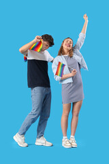 Fototapeta premium Happy young couple with LGBT flags on blue background