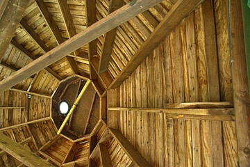 View looking up to the ceiling of a wood gazebo. Brown wood with Straight and angled. 
