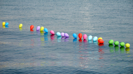 Colorful air balloons in a line floating on calm sea surface