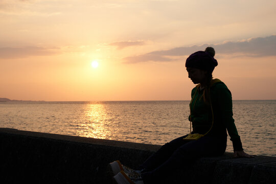 淡路島西海岸で沈む夕陽を眺める女性