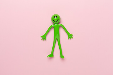 Human figure toy on color background, top view