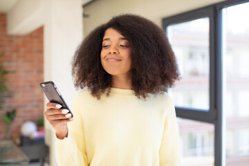 pretty afro black woman smiling and looking with a happy confident expression. smartphone concept