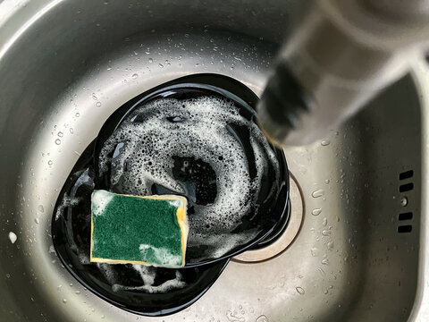 Washing Dishes. Soapy Plates With Foam And Dishwashing Lip, Sponge In The Kitchen Sink, Top View