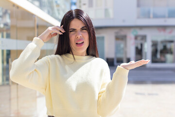 Fototapeta premium young pretty woman feeling confused and puzzled, showing you are insane, crazy or out of your mind