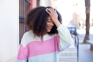 african american pretty woman laughing and slapping forehead like saying d’oh! I forgot or that...