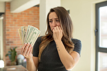 pretty woman feeling scared, worried or angry and looking to the side. dollar banknotes concept