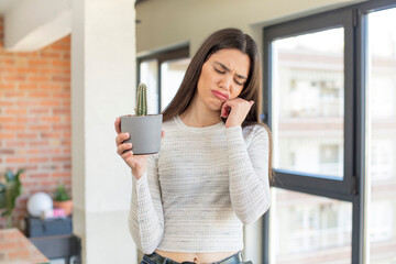 pretty young model feeling bored, frustrated and sleepy after a tiresome. decorative cactus concept