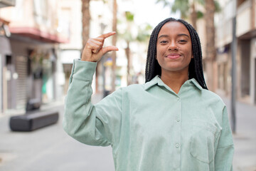 afro pretty black woman holding an object ,showing, offering or advertising something small