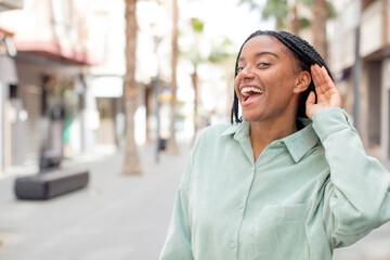 afro pretty black woman looking happy, listening, trying to hear a secret conversation or gossip,...