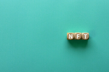 There is wood cube with the word NFT. It is an abbreviation for Non-Fungible Token as eye-catching image. - obrazy, fototapety, plakaty