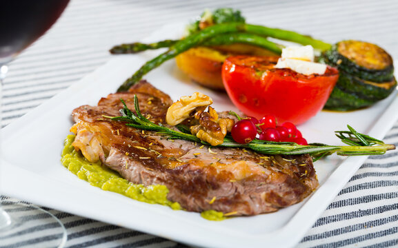 Image of veal with baked vegetables on the plate indoors.