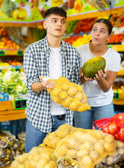 Happy young married couple who came to the store for shopping, chooses products to buy them