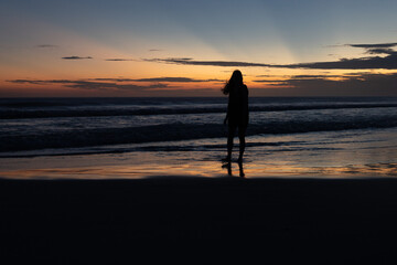 Fototapeta premium woman walking on the beach at sunset