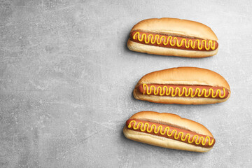 Fresh delicious hot dogs with mustard on light grey table, flat lay. Space for text