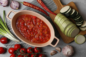 Dressing for ratatouille and different fresh vegetables on light grey table, flat lay