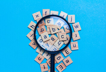 English alphabet made of square wooden tiles with the English alphabet scattered on blue...