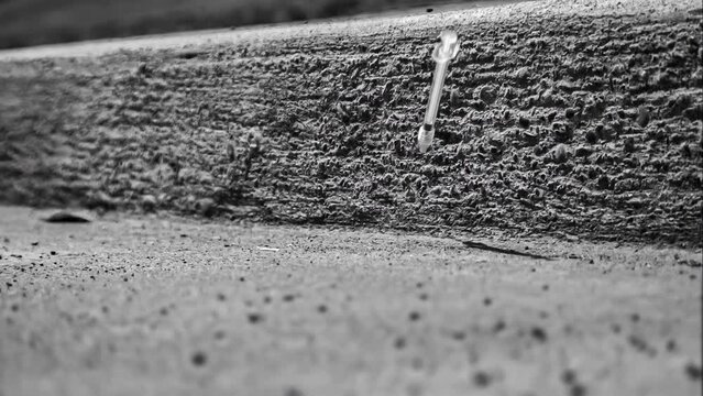 Plastic hypodermic needle dropping into a dirty city gutter; drug epidemic theme; 1000fps black and white slow motion video clip