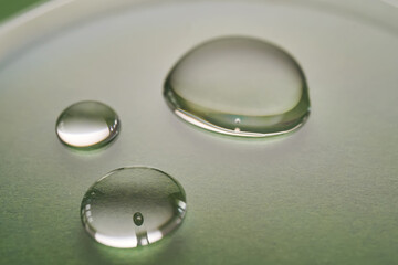Three drops of liquid on a green background.