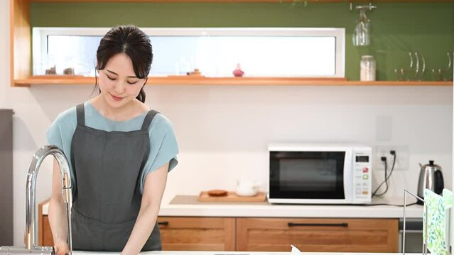 キッチンで料理をするかわいい奥さん　主婦の炊事家事イメージの動画