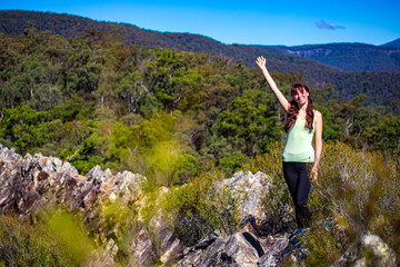 Naklejka na ściany i meble A beautiful girl celebrates a successful climb of the Pages Pinnacle and enjoys the view while standing on the narrow Razorback ridge. Hidden gems in Springbrook National Park, Gold Coast, Queensland 