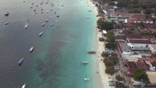 Beautiful beach on Gilli Trawangan with boats floating on the turquoise waters revealing mountains on the horizon in Bali
