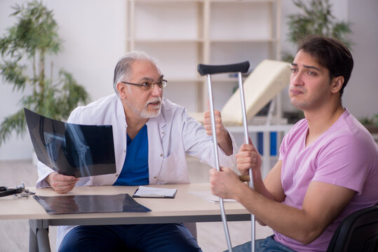 Young leg injured patient visiting old male doctor radiologist