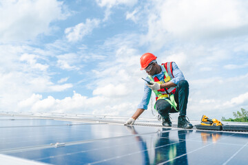 Fototapeta African American engineer maintaining solar cell panels on factory building rooftop. Technician working outdoor on ecological solar farm construction. Renewable clean energy technology concept obraz