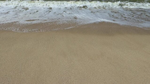 Soothing waves crashing on shore of sandy beach. Show motion video