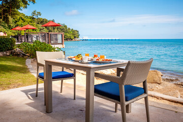 Breakfast table full of food at seaside restaurant, with sea view. Summer dinner at a beachfront...