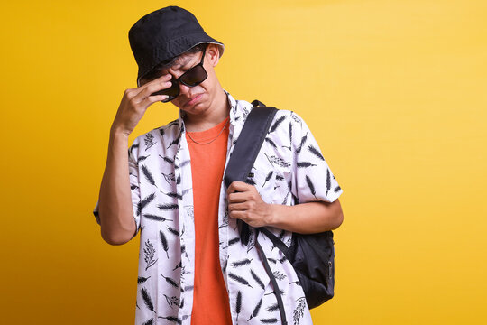Young Asian man tourist in summer beach outfit with backpack isolated on yellow background unhappy and frustrated with something. Negative facial expression