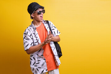 Excited traveler tourist Asian man in summer beach outfit clapping hands give appreciation isolated on yellow background. Travel advertisement and holiday concept. 