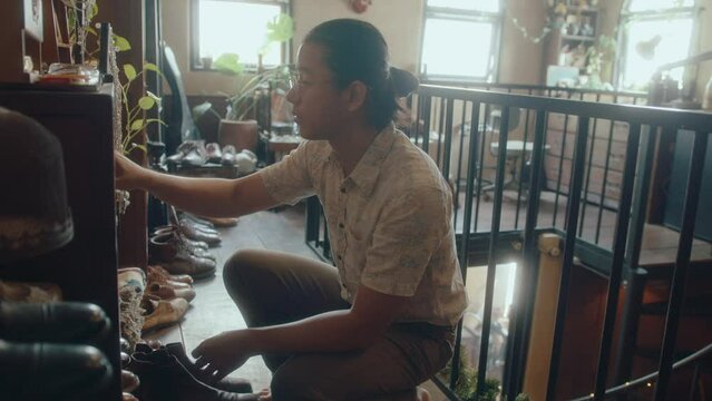 Young Asian antiques collector checking old things in his vintage shop, taking care or doing inventory of items