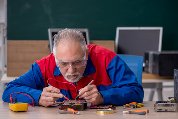 Old repairman repairing computers in the classroom