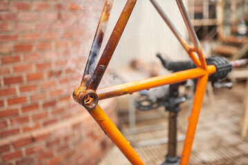 Manual bicycle renovation work, paint removal process using a torch fire to change the color of a...