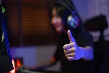 Female cyber hacker gamer in headphone showing thumb up after hacking programming system success