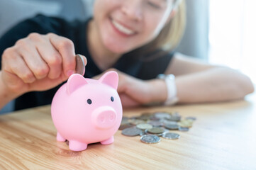 Happiness woman while putting a coin into piggy bank for saving money.
