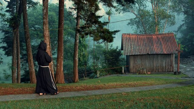 Fraile franciscano religioso cristiano cat&oacute;lico meditando o rezando por el bosque en el camino contemplando la naturaleza en un hermoso d&iacute;a al amanecer caminando por el camino cerca de una casa choza