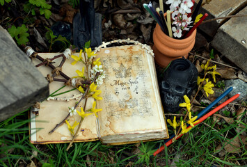 Magic book of spells, candles and pentagram on ritual altar in grass. Occult, esoteric and...