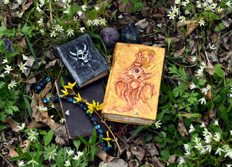 Decorated magic books of spells on the grass in the garden. Occult, esoteric and divination still...