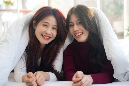 Portrait of couple lesbian in bedroom. They looking to camera with smiling.