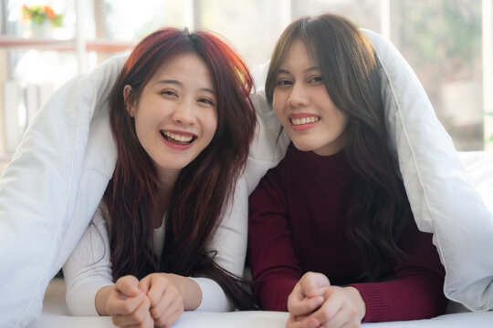 Portrait of couple lesbian in bedroom. They looking to camera with smiling.