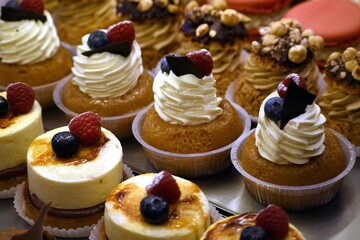Large choice of beautiful pastries, sweet and colorful background. Cream, berries and fruits.