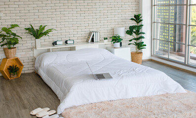 White clean sheet bed with pillows and blanket in modern trendy decoration bedroom with glass windows home apartment with carpet on floor.