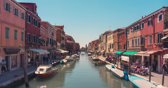 Static timelapse shot of Murano canal with colorful houses and blue sky during summer day