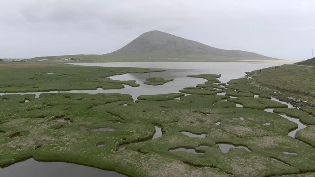 Aerial view of Northton Saltmarsh on an overcast day on the Isle of Harris, Outer Hebrides, Scotland, UK. Flying over the saltmarsh towards the sea.