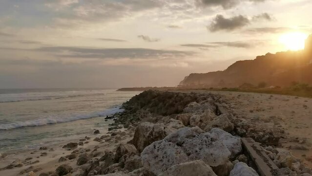 Colorfull sunset at the emtpty beach in Melasti, Uluwatu on the penisula in Bali Indonesia. The sky has beautiful colors the sun sets behind the cliff in the golden hour.